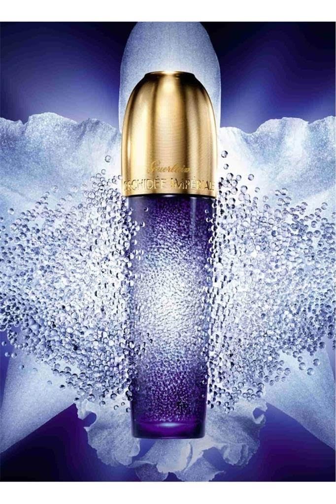Blauw-paarse fles met gouden dop. Opschrift: Guerlain Orchidée Impériale. Omringd door witte parels.
