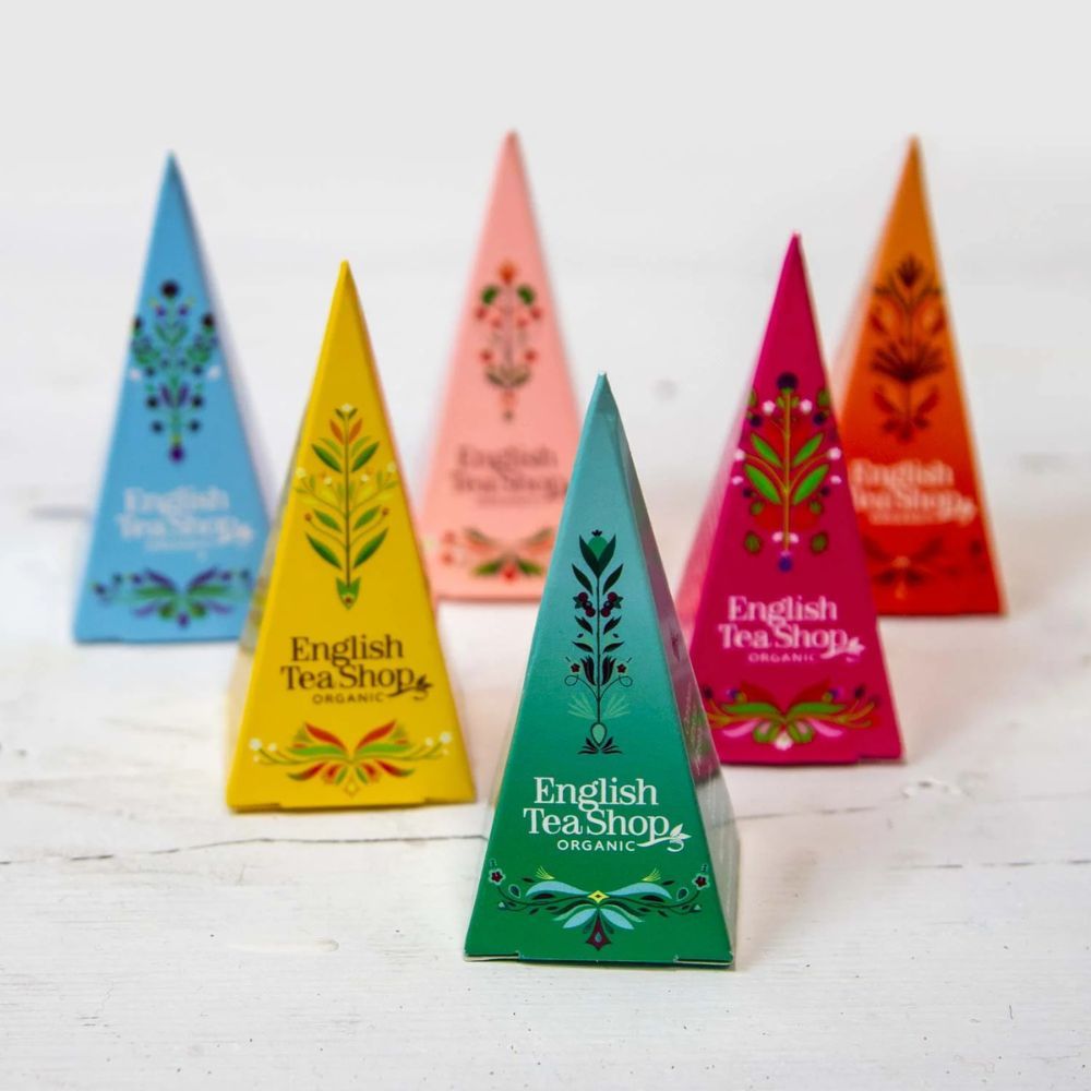 Zes gekleurde piramide theezakjes. Opschrift: English Tea Shop Organic. Verschillende kleuren: blauw, geel, roze, groen, roze, oranje.