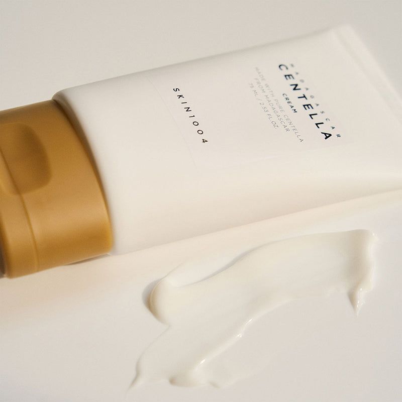 Tube avec crème à côté. Inscription: MADAGASCAR CENTELLA CREAM, SKIN1004. Crème visible.