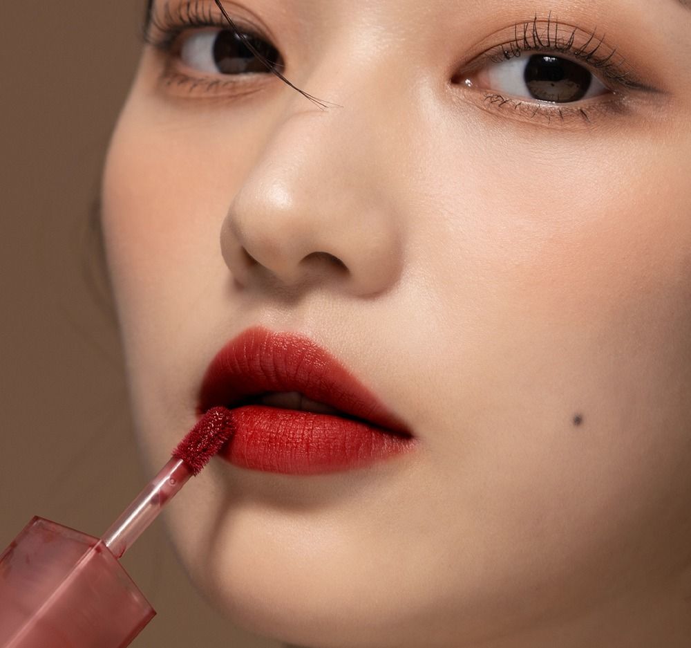 Gros plan sur un visage avec des lèvres rouges. Applicateur de gloss.