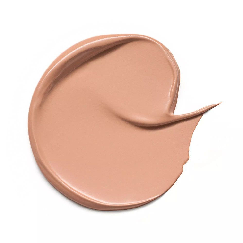 Trace de correcteur beige sur fond blanc. La texture est lisse et mate.