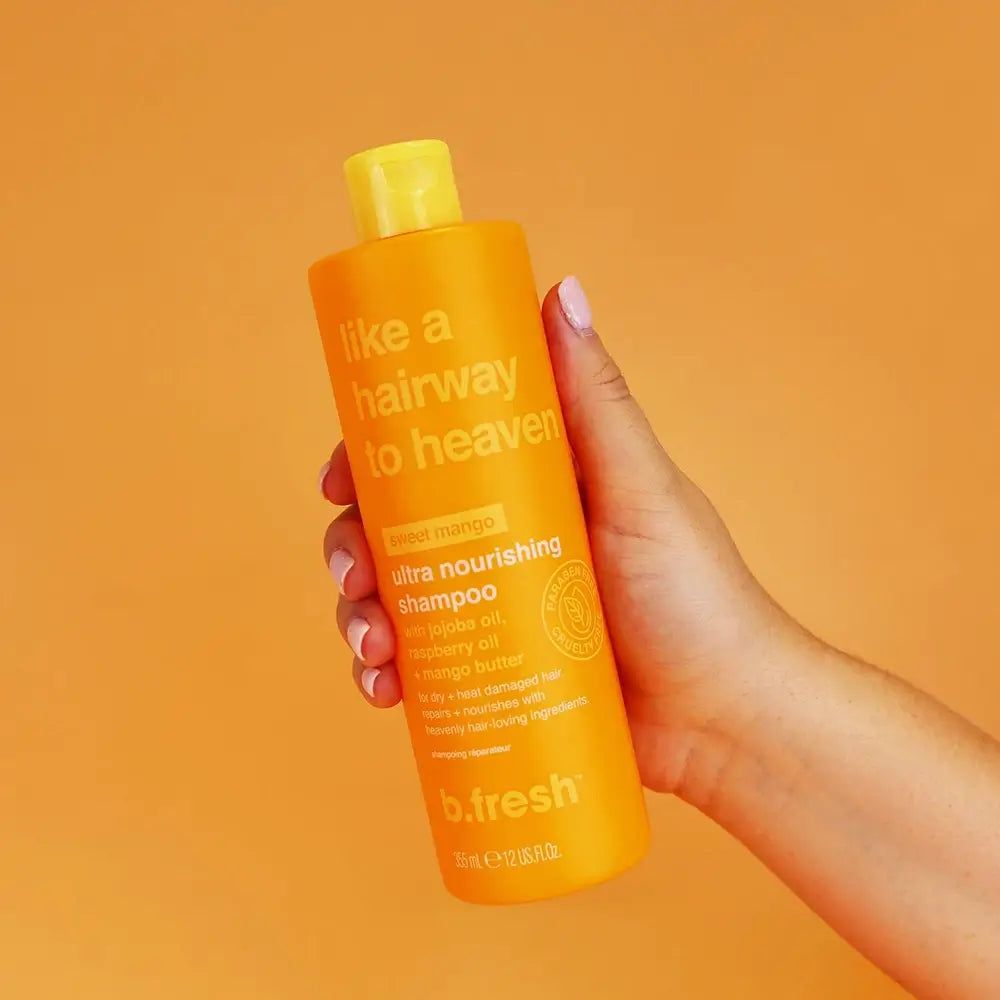 Flacon de shampooing orange, tenu par une main. Inscription : "like a hairway to heaven" et "b.fresh".