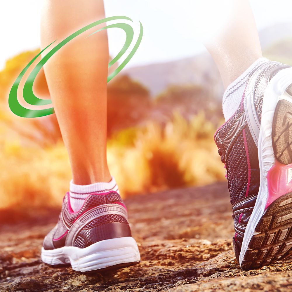 Close-up van benen tijdens het hardlopen. Groene cirkels rond het been. Sportschoenen op een rotsachtig pad.