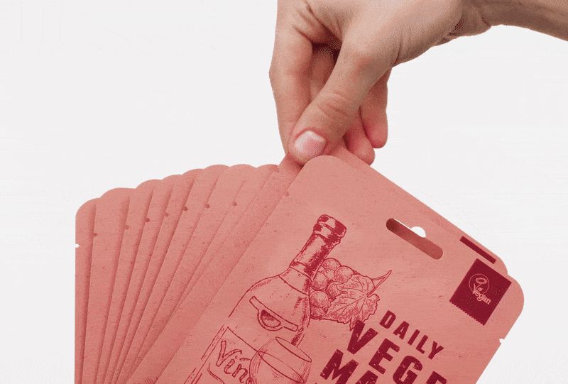 Hand houdt meerdere roze masker verpakkingen vast. Opdruk: DAILY VEGE MASK, wijn illustratie. Verpakkingen met ophanggat.