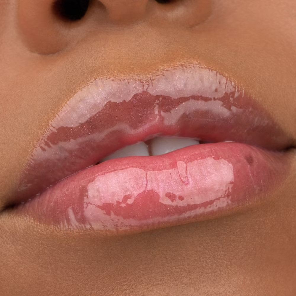 Gros plan sur des lèvres avec un gloss rose brillant.