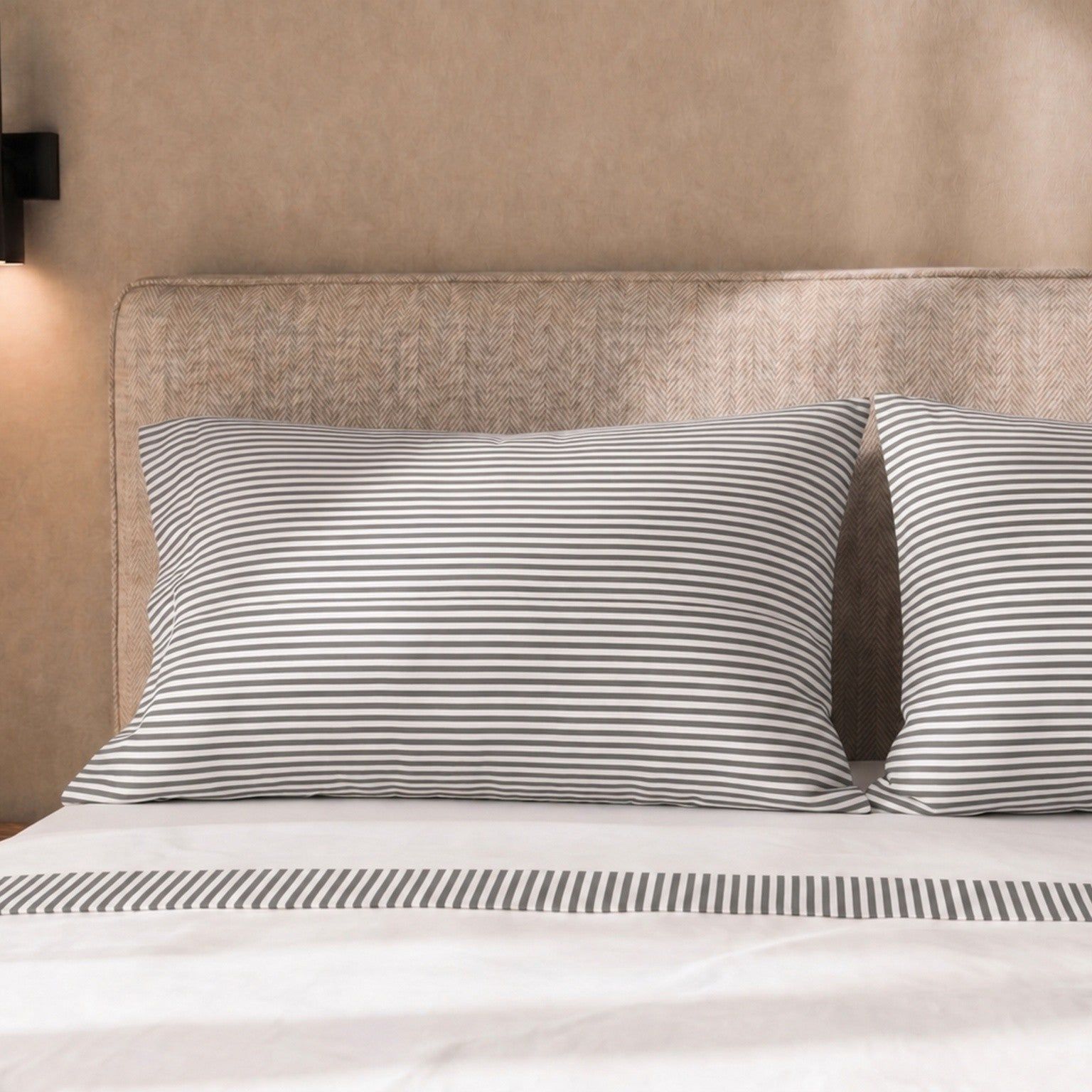 Bed met gestreepte kussenslopen en beddengoed met streepjesaccent.