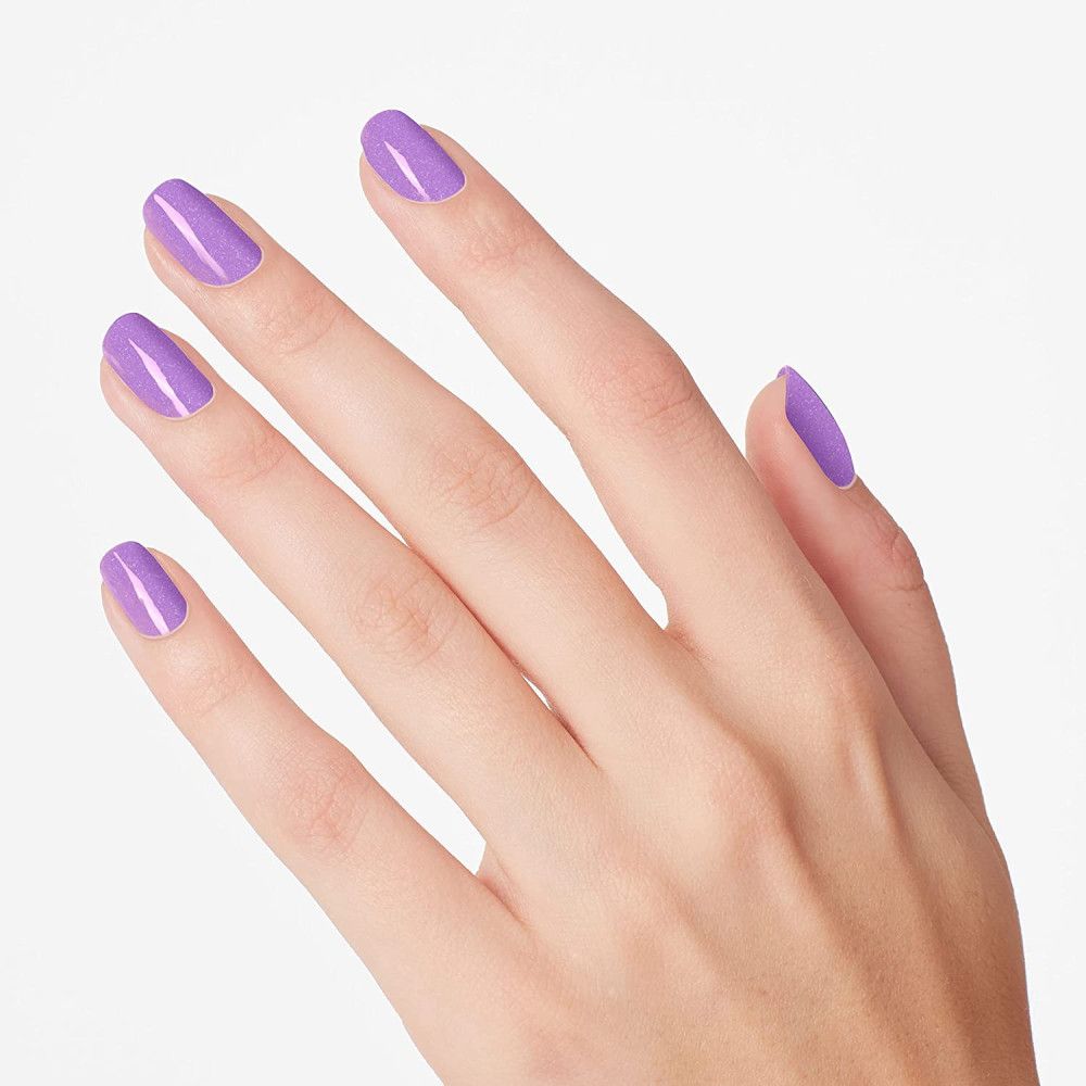 Main avec ongles vernis en lilas. Cinq ongles vernis.