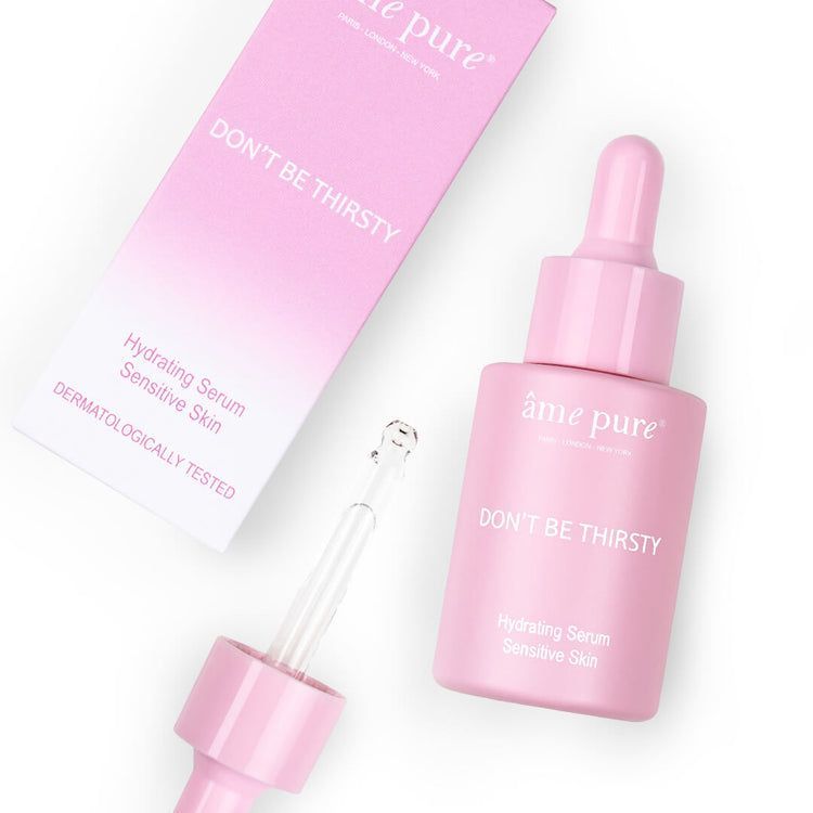 Un flacon rose à pipette et sa boîte ouverte du sérum visage "Don't Be Thirsty".