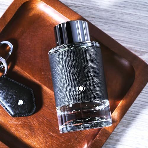 Flacon noir avec bouchon argenté sur plateau en bois. Logo Montblanc. Porte-clés avec logo.