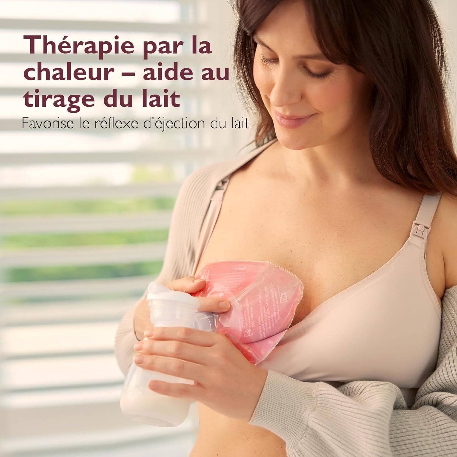 Une femme tient une compresse chauffante et un biberon contre sa poitrine.