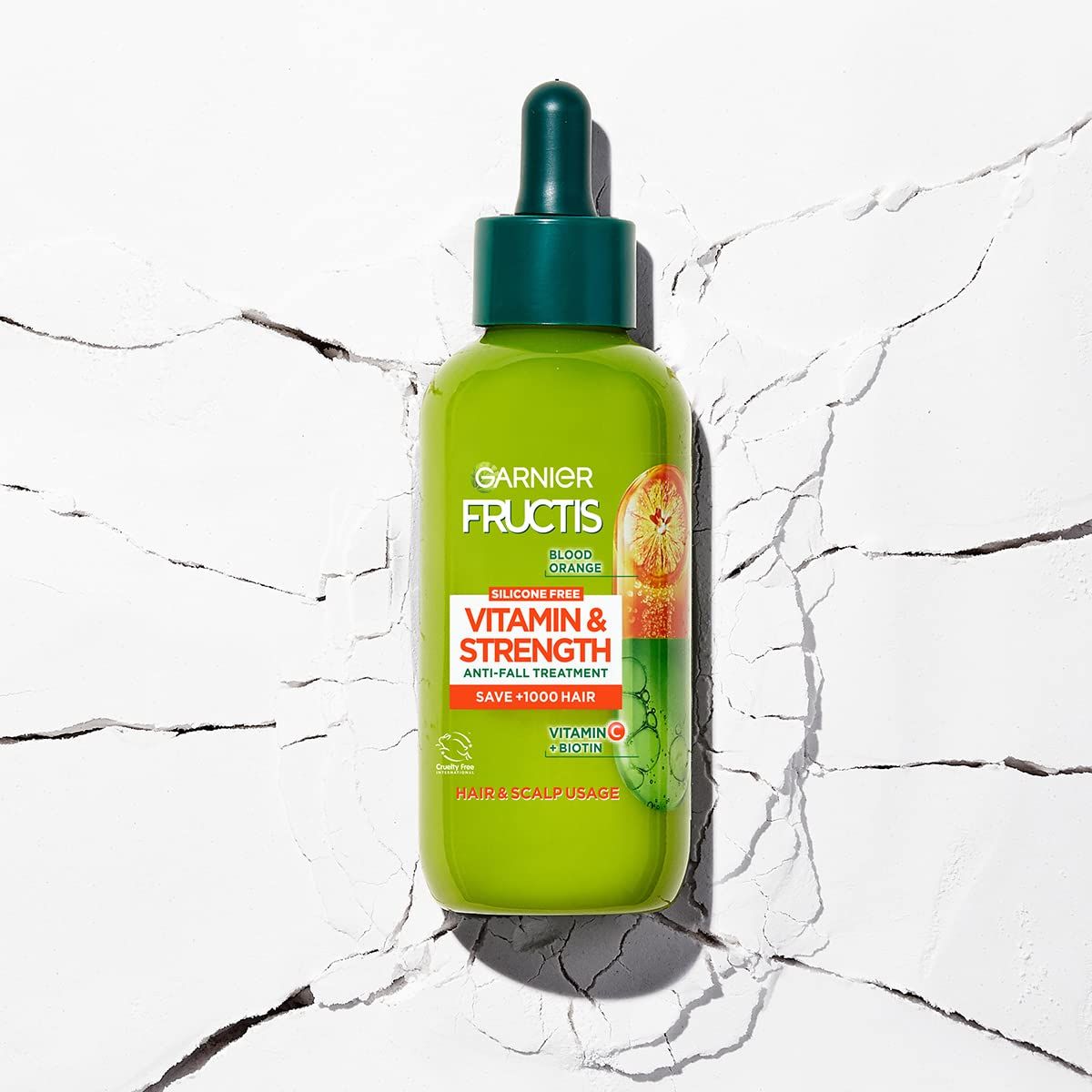 Groene fles met druppelaar. Opschrift: Garnier Fructis Vitamine & Kracht. Anti-haaruitval behandeling. Bevat Vitamine C & Biotine.