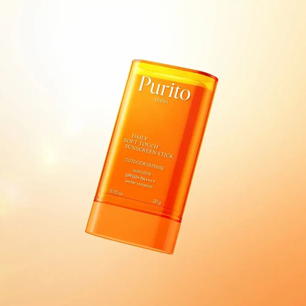 Stick de protection solaire orange flottant. Texte: Purito, Daily Soft Touch Sunscreen Stick, SPF50+ PA++++, 0.70 oz, 20 g.