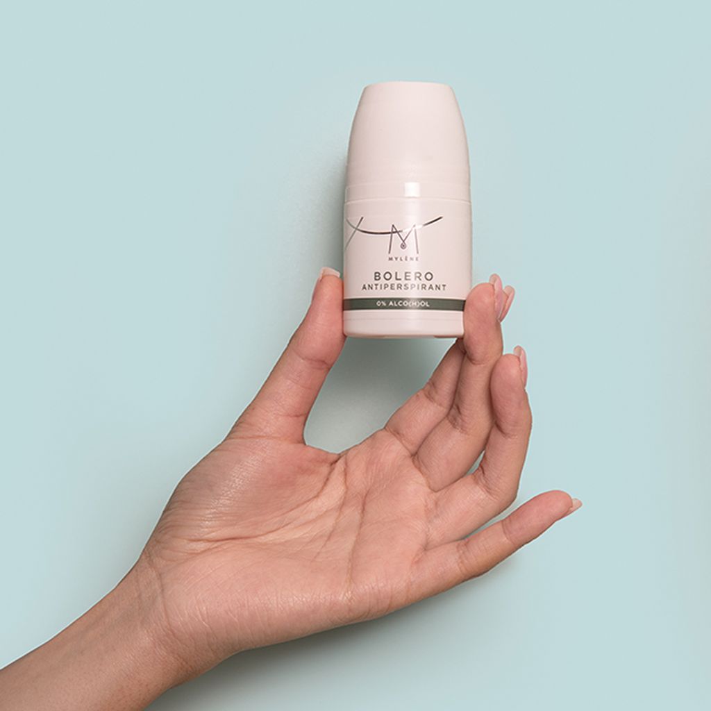 Deodorantroller in hand. Witte behuizing, zwarte tekst: Mylène, Bolero, Antitranspirant, 0% Alco(h)ol. Achtergrond: lichtblauw.