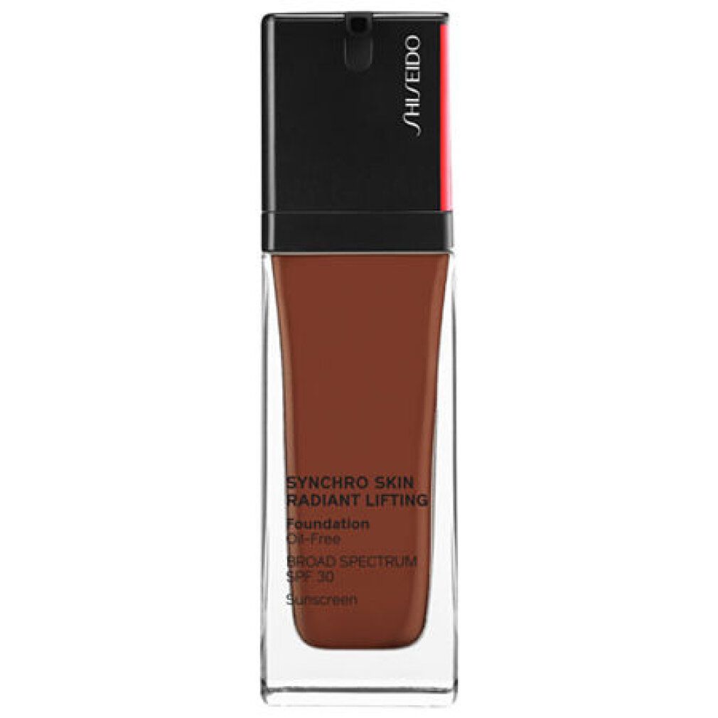 Flacon de fond de teint brun. Bouchon noir avec accent rouge. Inscription: Synchro Skin Radiant Lifting Foundation, SPF 30.