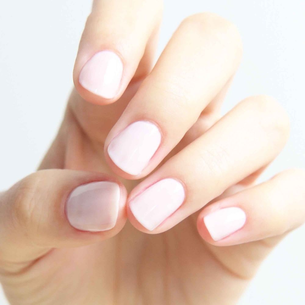 Hand met lichtroze gelakte nagels. Verschillende tinten roze op de nagels.