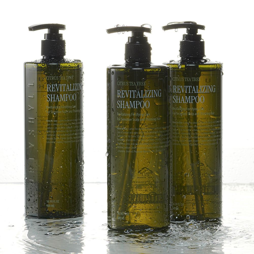 Drie groene shampoo flessen met zwarte pompen. Opschrift: Revitalizing Shampoo. Water op het oppervlak.