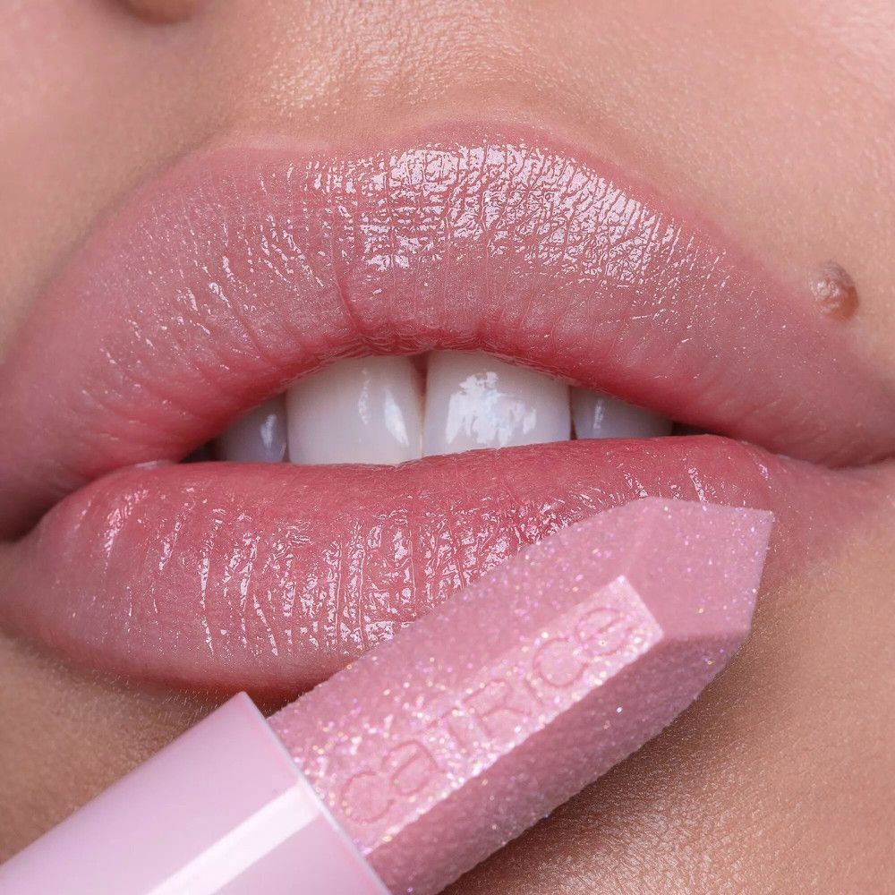 Close-up van lippen bedekt met roze lippenbalsem. De lippenbalsem wordt aangebracht. Merk: Catrice.