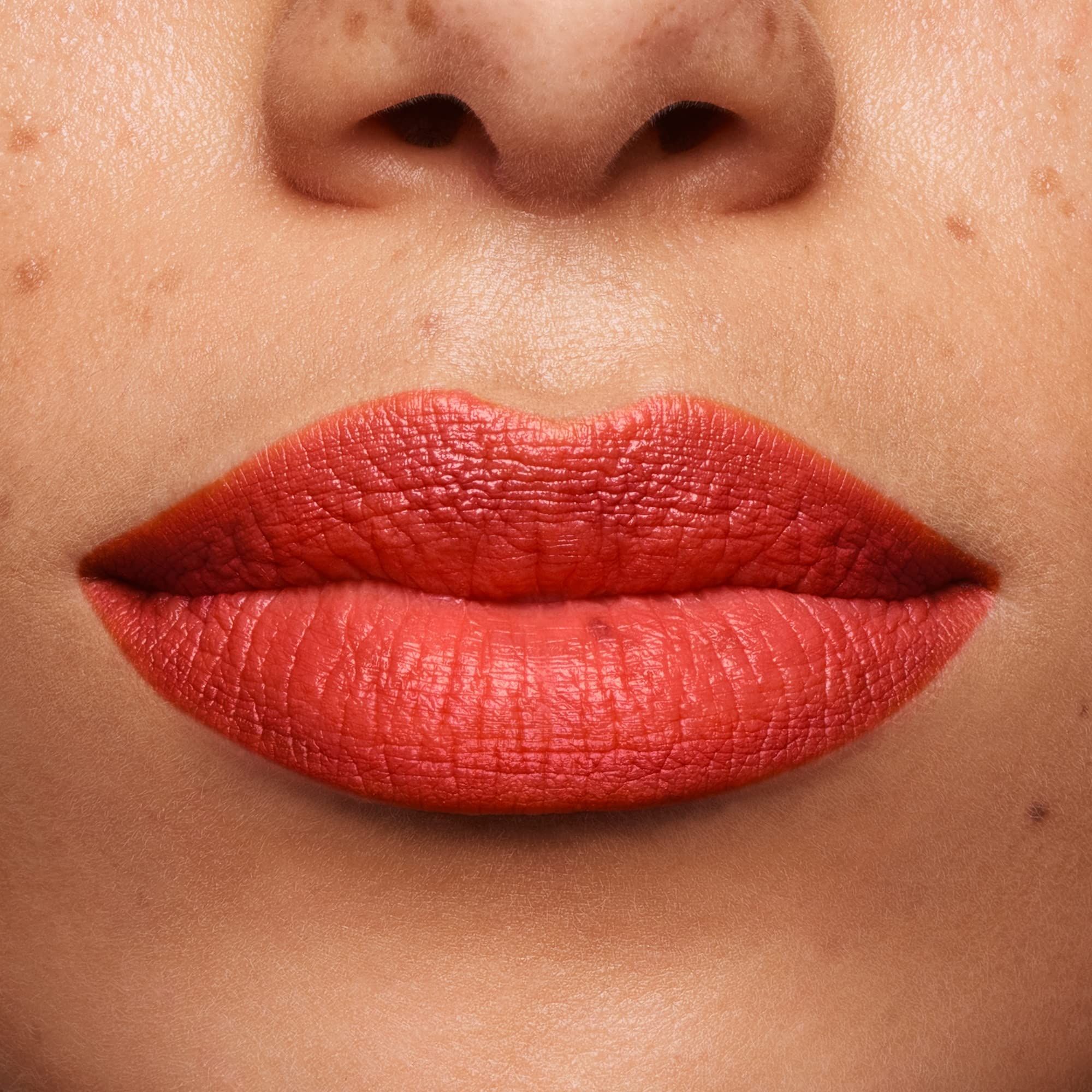 Gros plan sur des lèvres recouvertes de rouge à lèvres orange. Teint.