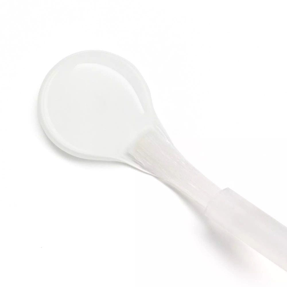 Gros plan du pinceau d'un exfoliant cuticules. Le pinceau est blanc et de forme ovale.