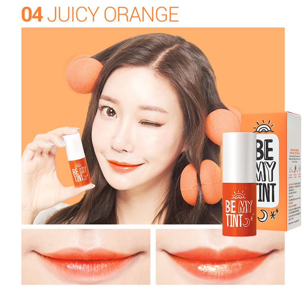 Femme avec brillant à lèvres orange. Produit et emballage. Texte: BE MY TINT, 04 Juicy Orange. Fond orange.