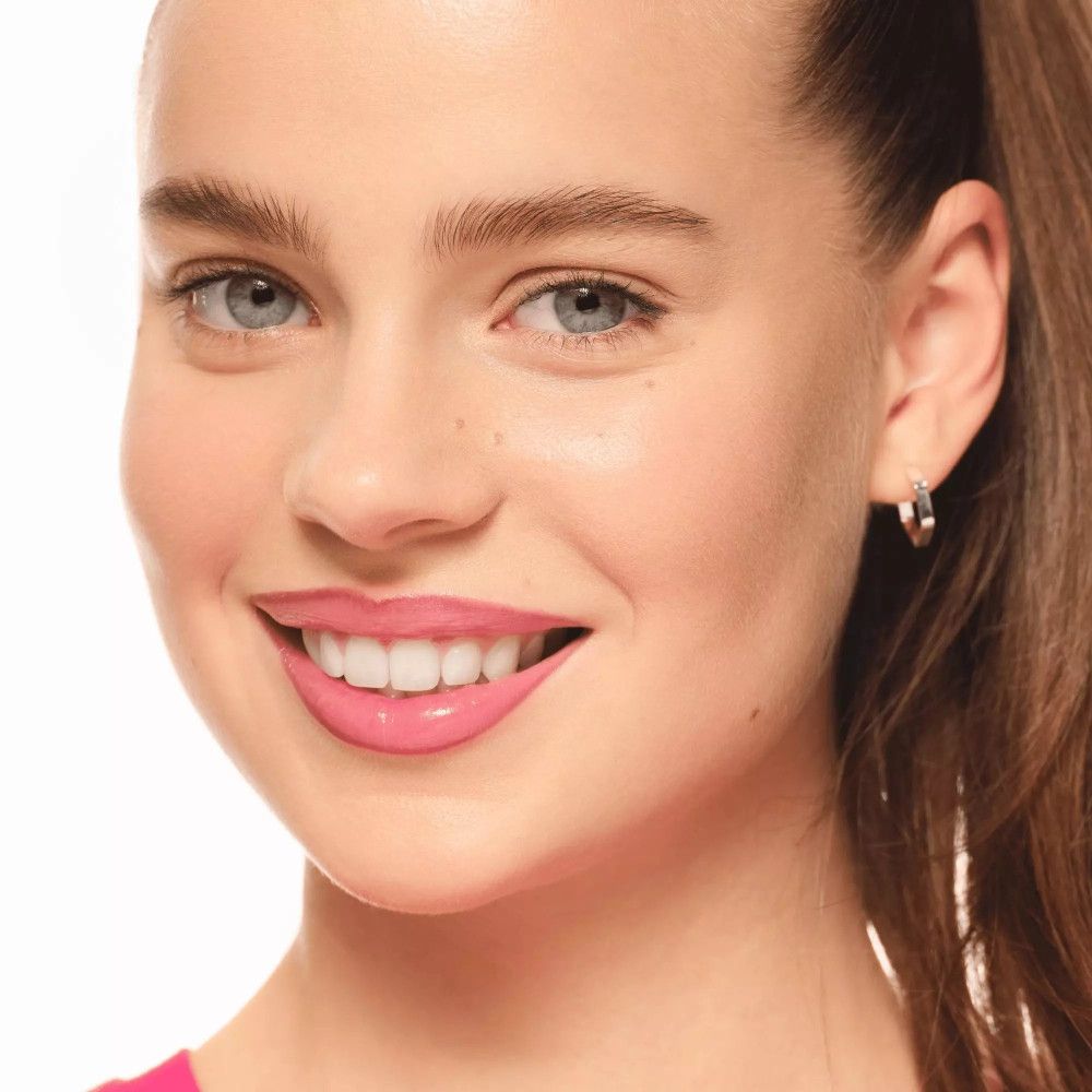 Vrouw met roze lippenstift. Huid met sproeten. Zilveren oorbel.