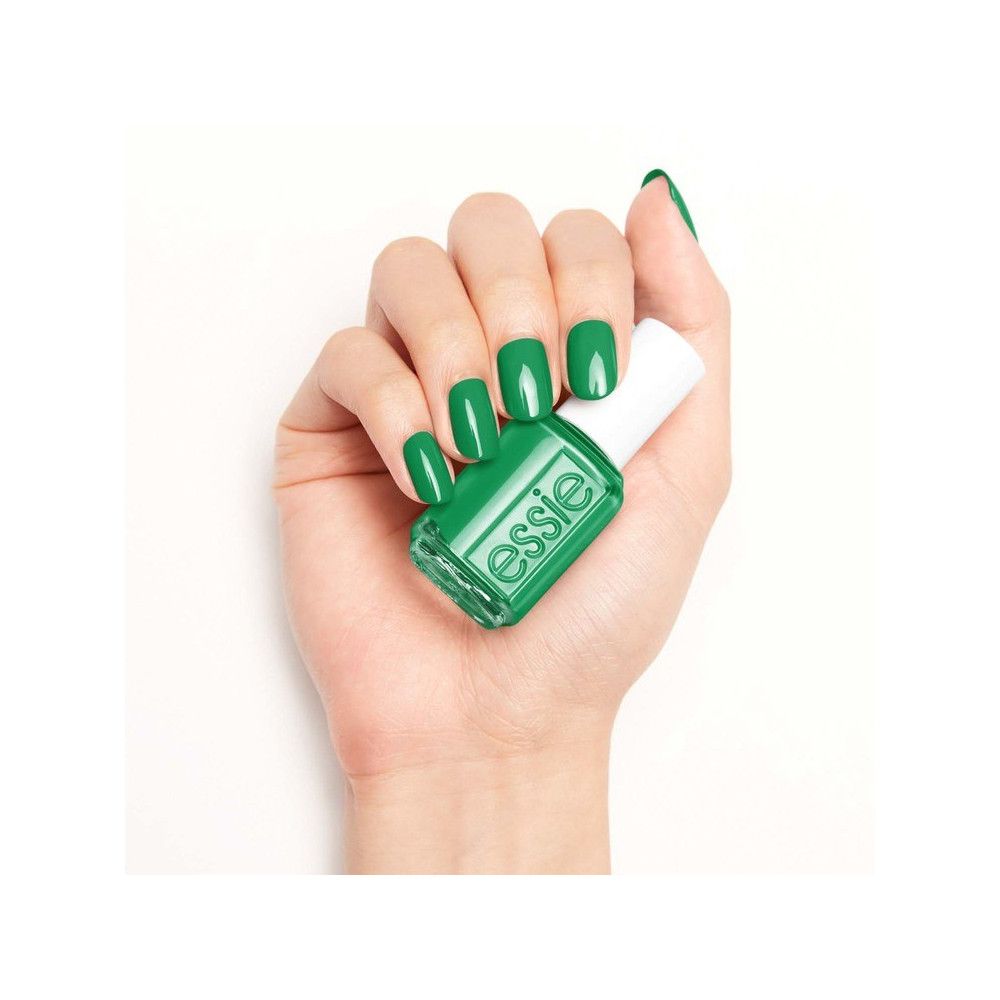 Hand met een fles nagellak en gelakte nagels. Fles met witte dop, groene lak.