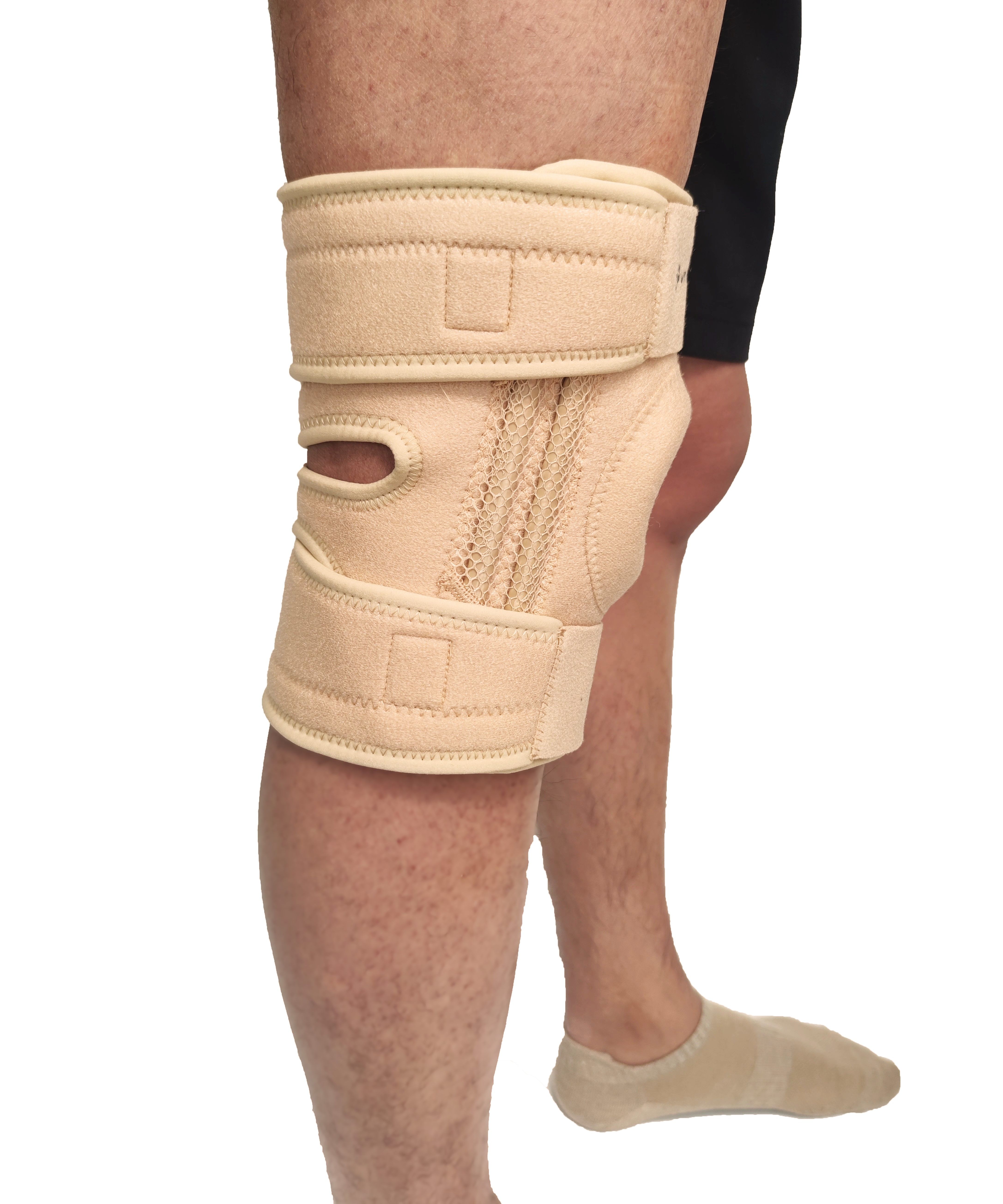 Genouillère beige sur une jambe. Fermetures velcro et ouverture rotulienne visibles.