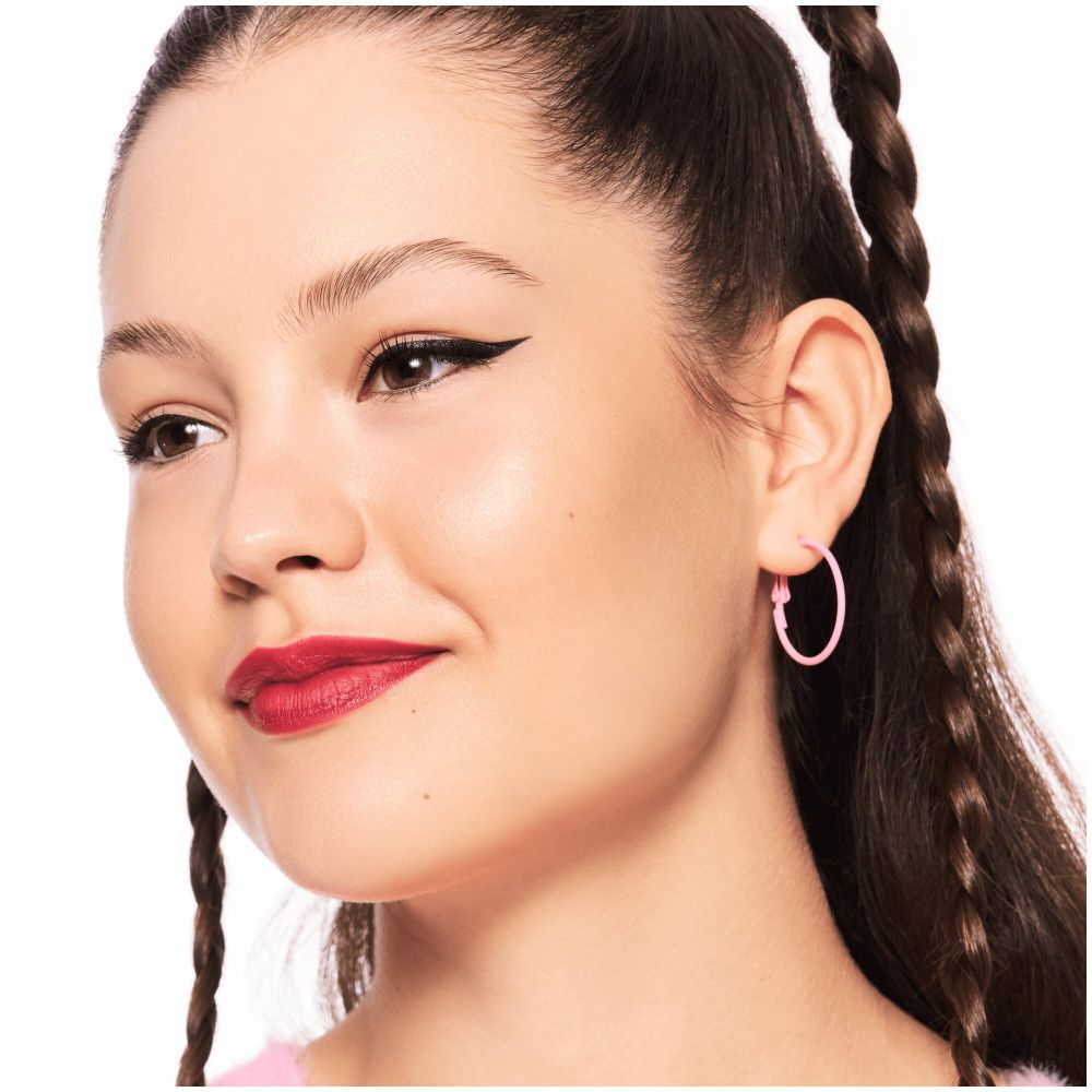 Portrait d'une fille avec créoles roses et eyeliner noir.