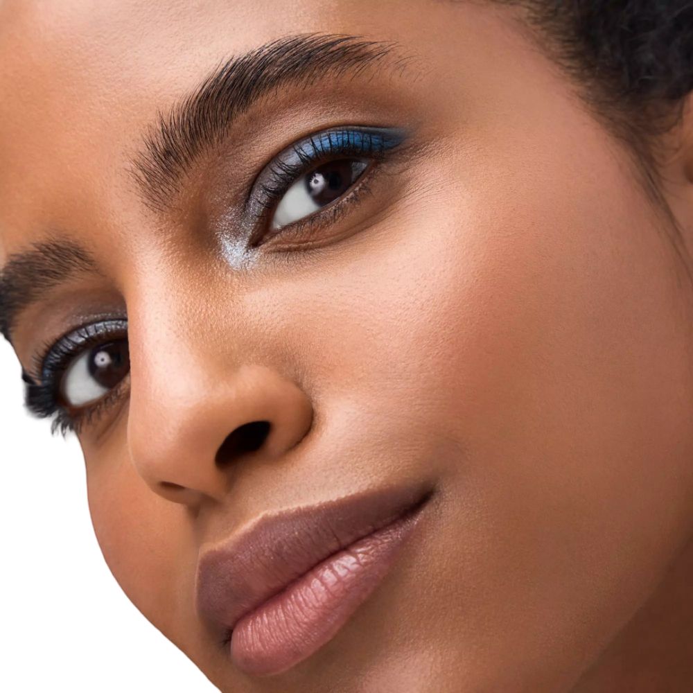 Close-up van een gezicht met blauwe eyeliner en oogschaduw. De huid is gebruind. De blik is naar boven gericht.