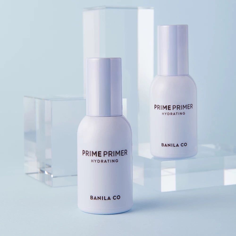 Twee witte flessen met pompen. Opschrift: PRIME PRIMER HYDRATING, BANILA CO. Op blauwe achtergrond.