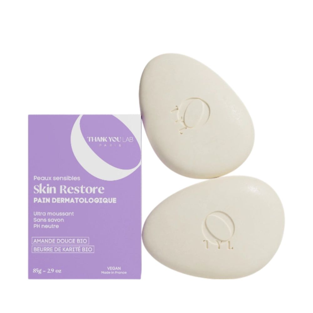 Deux pains de savon ovales et une boîte violette. La boîte indique "Skin Restore".