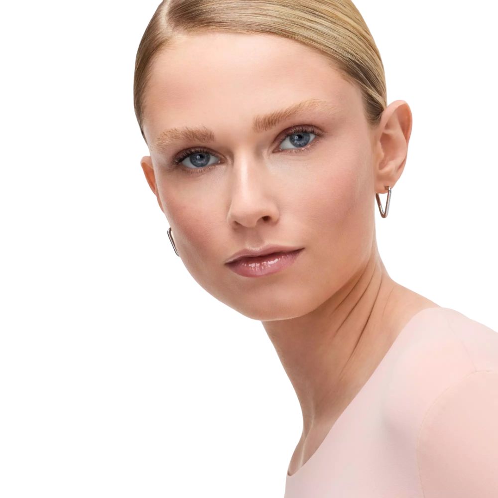 Portret van een vrouw met blond haar en zilveren oorbellen. Ze kijkt in de camera.