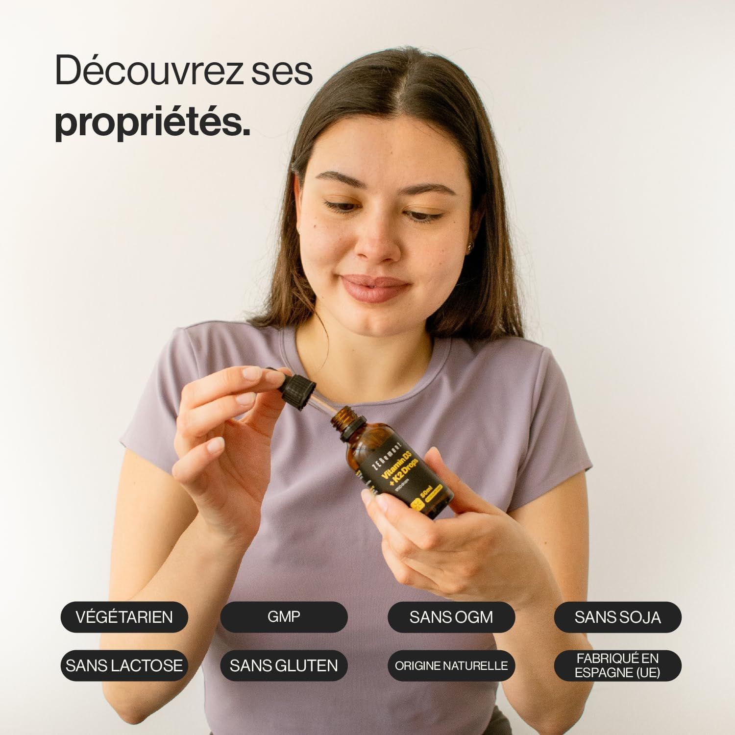 Femme tenant des gouttes Zenement Vitamine D3 + K2. Végétarien, GMP, sans OGM, sans soja, sans lactose, sans gluten, origine naturelle, fabriqué en Espagne.