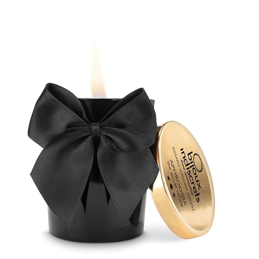 Bougie noire avec nœud et couvercle doré. Inscription sur le couvercle. Flamme allumée. Bijoux Indiscrets.