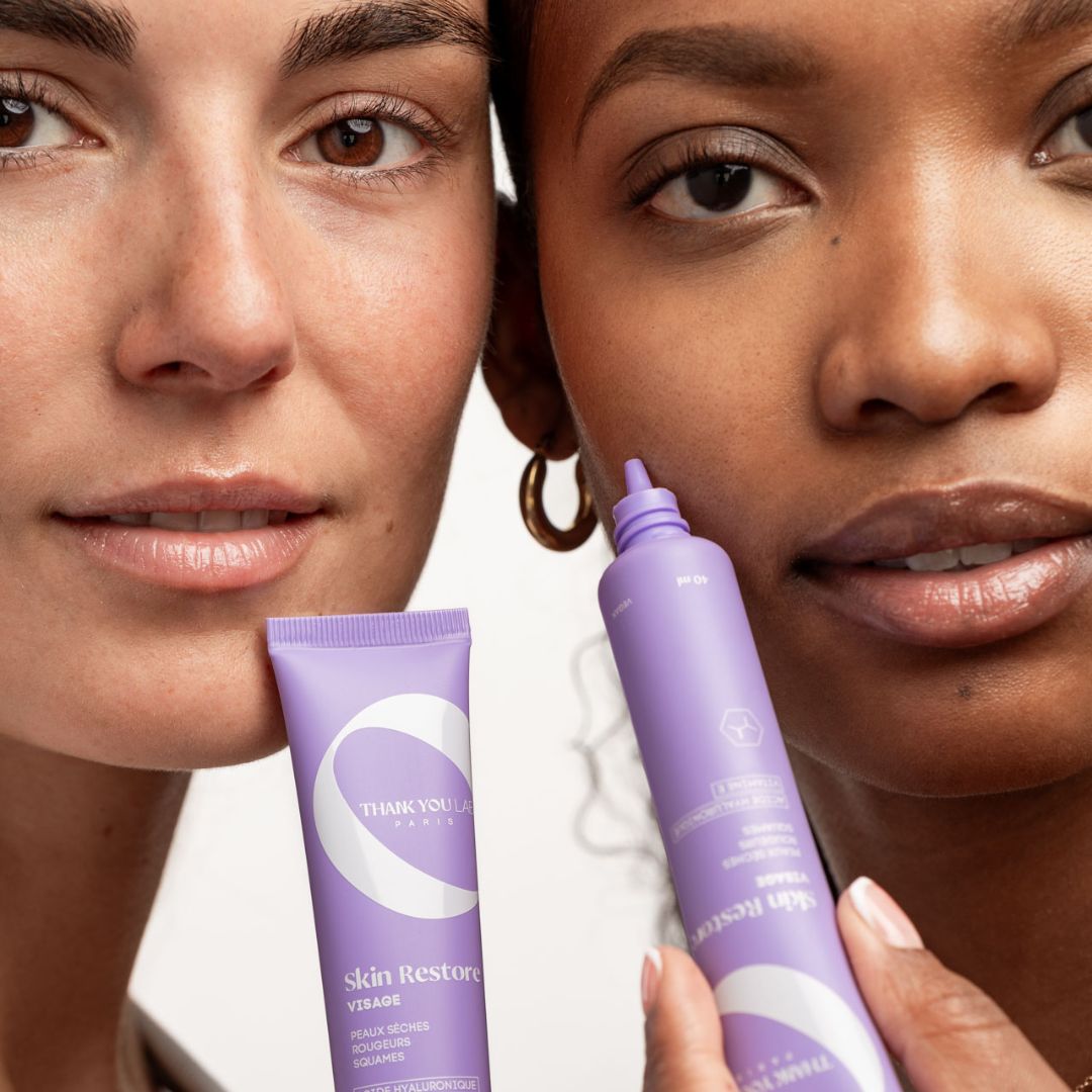 Twee vrouwen houden paarse tubes vast. Opschrift: THANK YOU LAB PARIS. Productnaam: Skin Restore Visage.