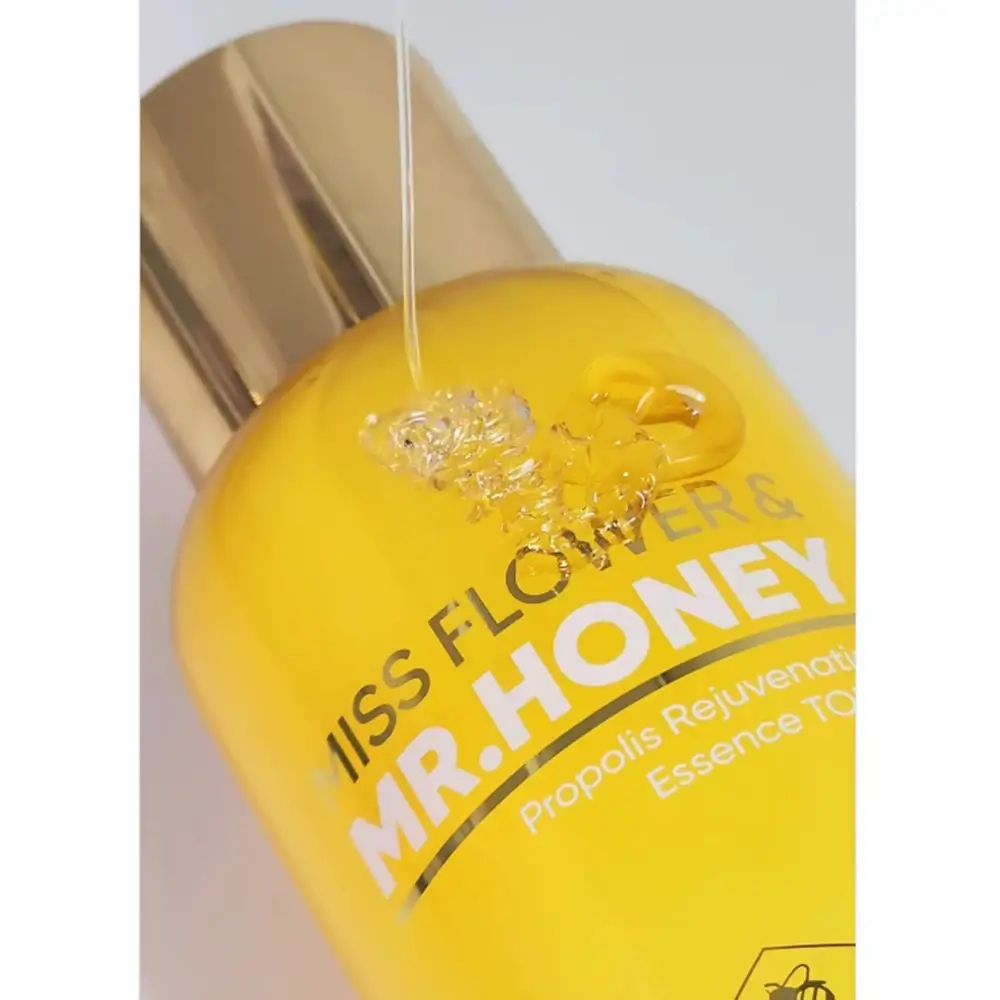 Close-up van een geel transparante fles met gouden dop. Opschrift: Miss Flower & Mr. Honey, Propolis Rejuvenating Essence Toner.