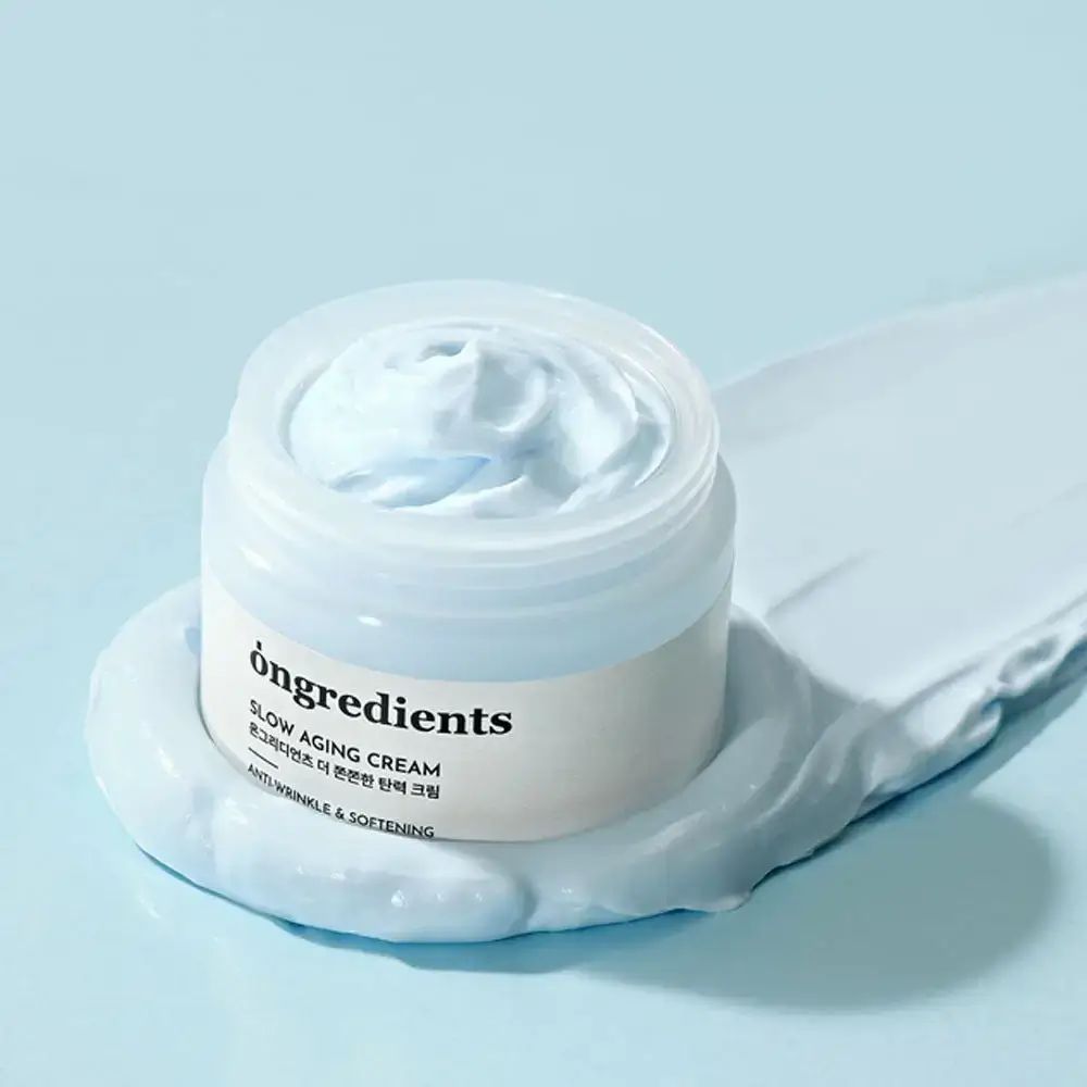 Pot de crème ouvert avec une goutte de crème. Inscription : Ongredients, Slow Aging Cream, Anti-Wrinkle & Softening.
