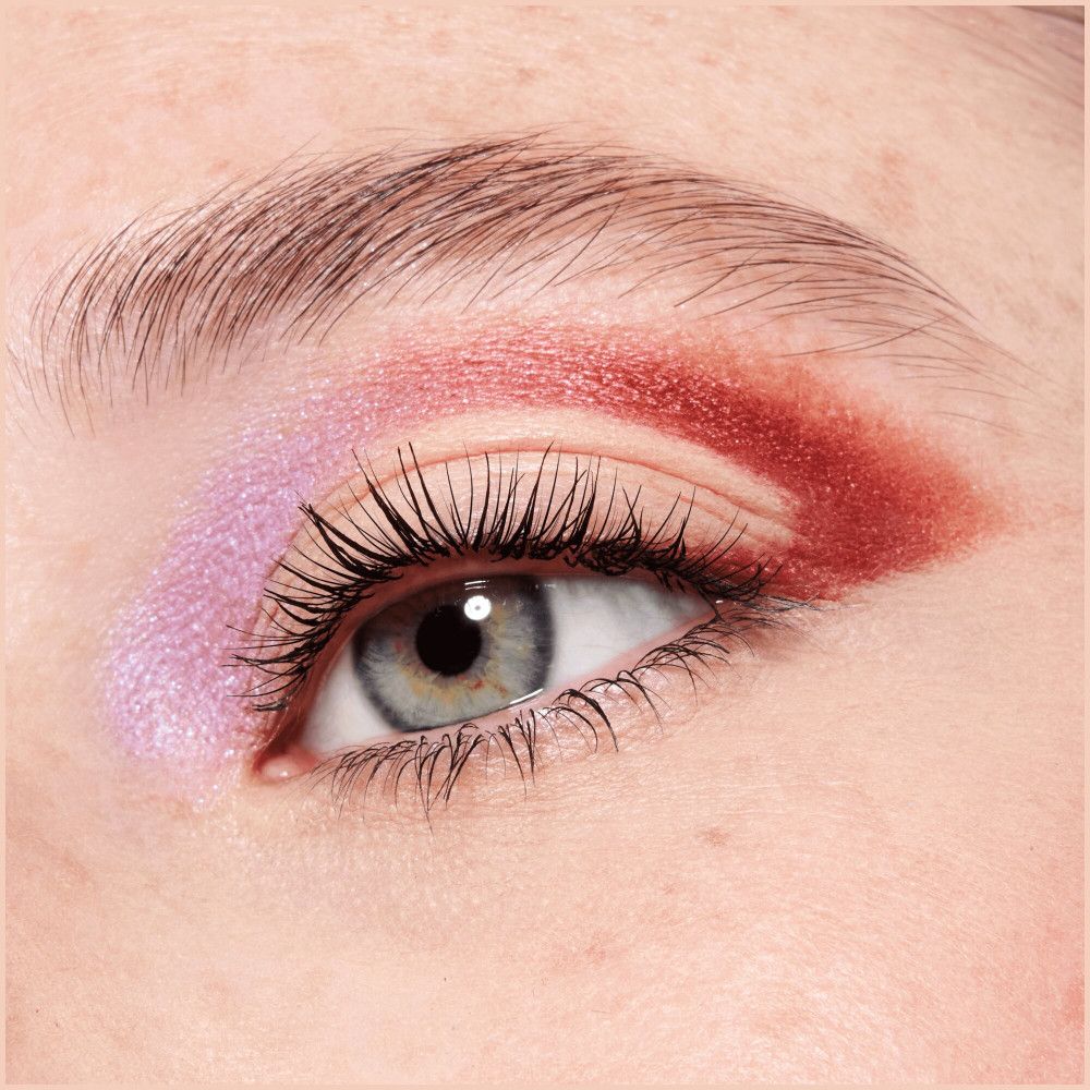 Œil avec fard à paupières et mascara. Fard à paupières violet et rouge. Cils maquillés. Fond bleu pour les yeux.
