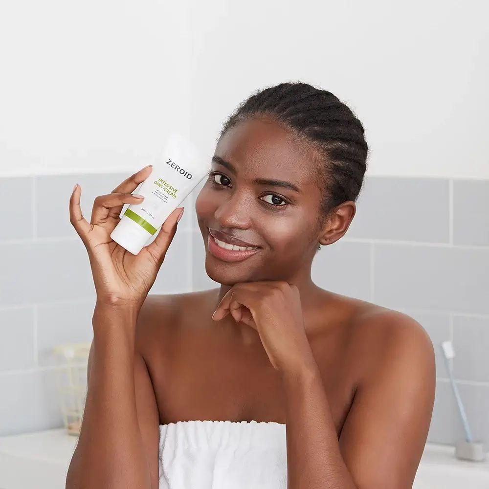 Vrouw houdt tube ZEROID INTENSIVE OINT-CREAM vast. Tekst: Intensieve verzorging voor droge huid. Vrouw lacht.