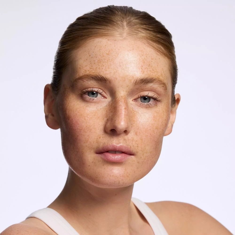 Gros plan sur un visage avec des taches de rousseur. La femme a la peau claire et les yeux bleus.