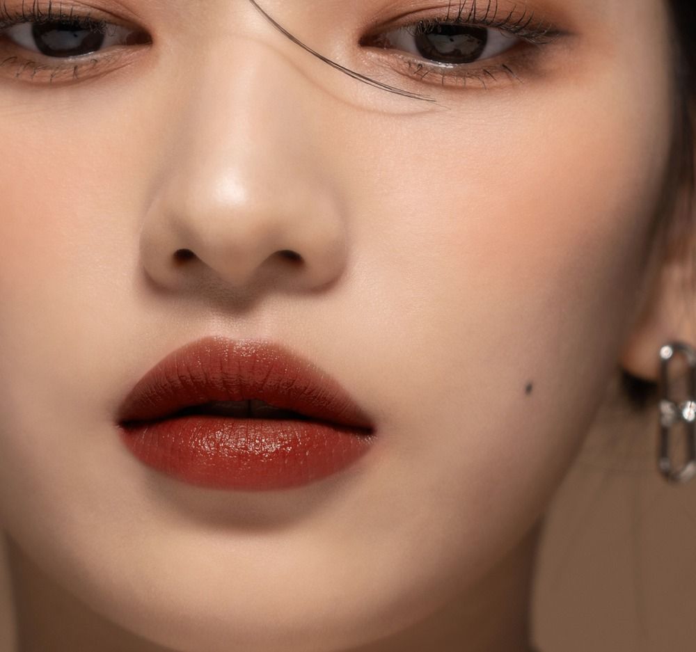 Gros plan sur les lèvres avec gloss. Teinte rouge foncé. Visage d'une personne.