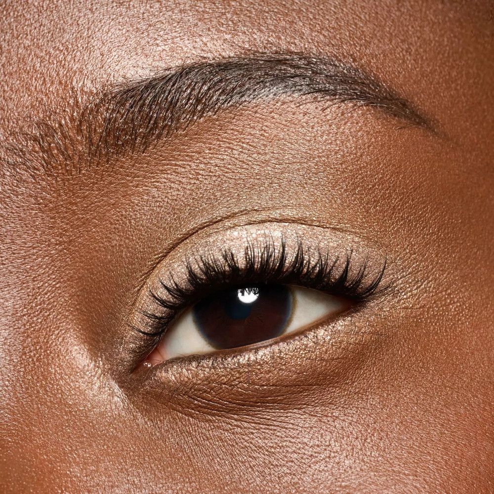 Gros plan d'un œil avec du fard à paupières crème. Le fard est clair et scintillant. Longs cils.