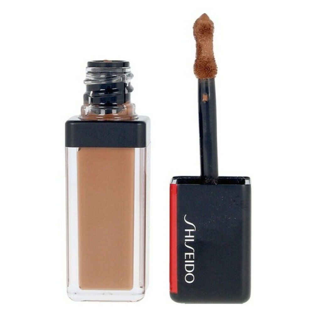 Bruine concealer in rechthoekige fles met zwarte dop. Applicator met spons tip. Shiseido logo.