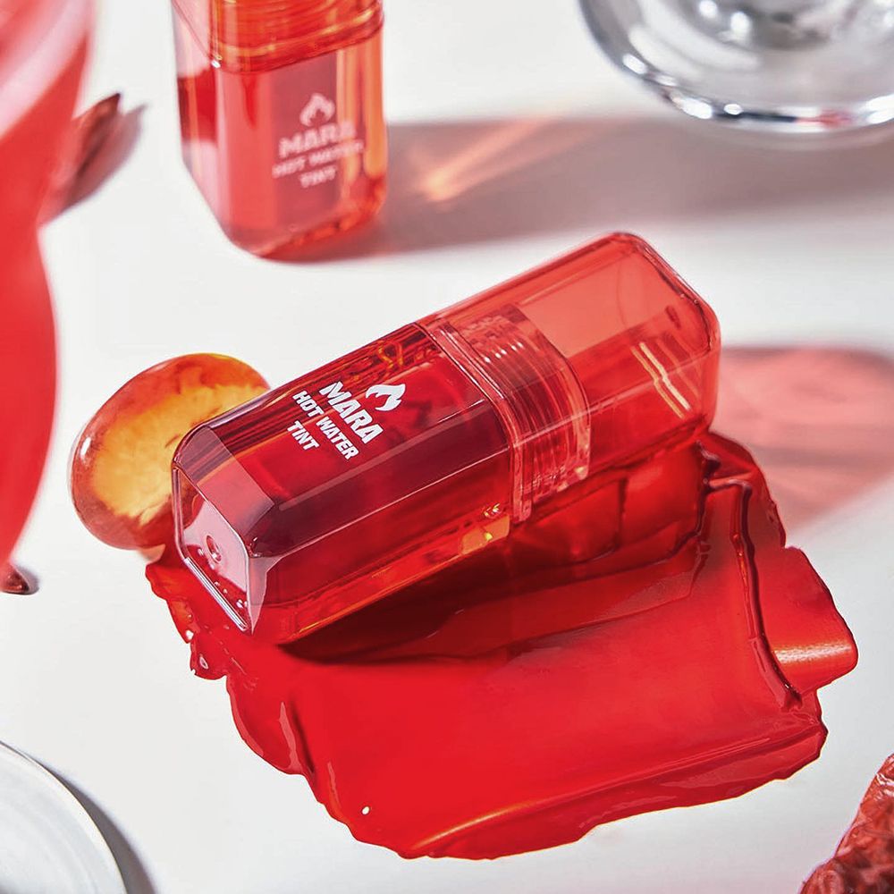 Rouge à lèvres rouge et tache sur fond blanc. Nom du produit: MARA HOT WATER TINT. Récipient supplémentaire.