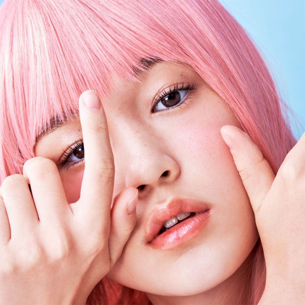 Close-up van een persoon met roze pruik. Glanzende lippen, handen in beeld.