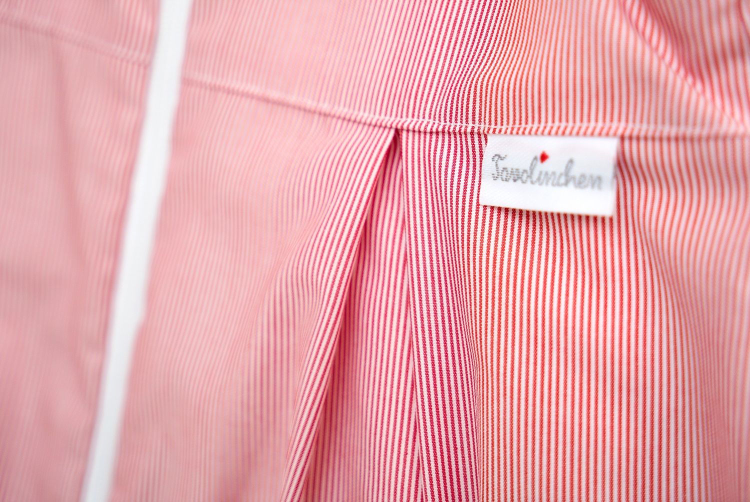 Vue détaillée de la gigoteuse à rayures rouges. Étiquette blanche avec le logo Tavolinchen.