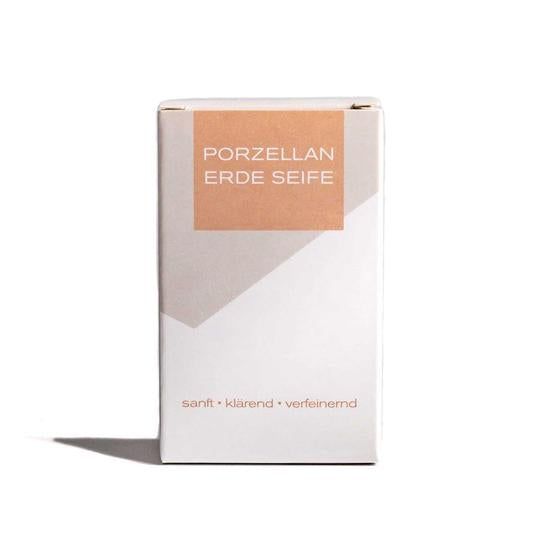 Emballage en carton blanc avec l'inscription PORZELLAN ERDE SEIFE. Texte en dessous : doux, clarifiant, affinant. Un rectangle beige en haut.