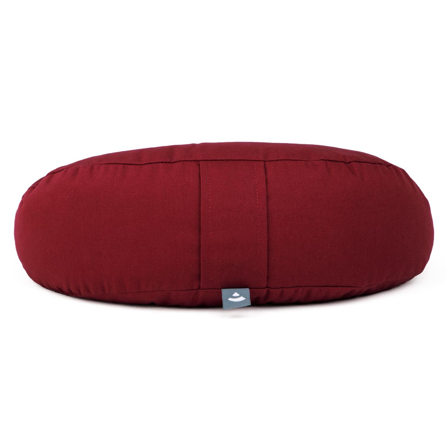 Coussin de méditation rond bordeaux avec une petite étiquette logo sur le côté.