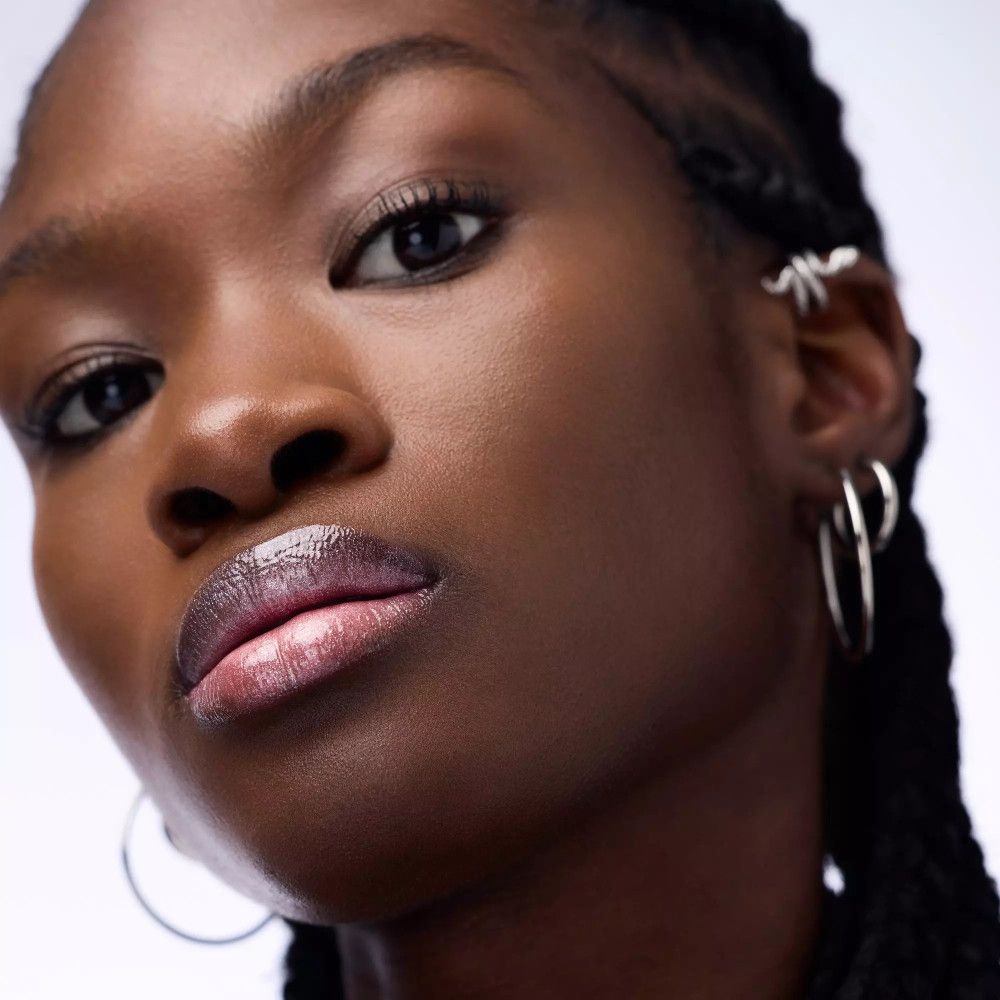 Close-up van een gezicht met lipgloss op de lippen. Donkere huid, gevlochten haar.