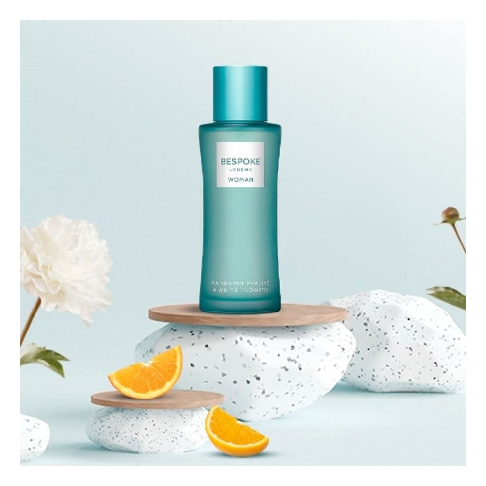 Flacon turquoise avec étiquette blanche. Sur socle avec oranges et décorations. Bouchon turquoise.